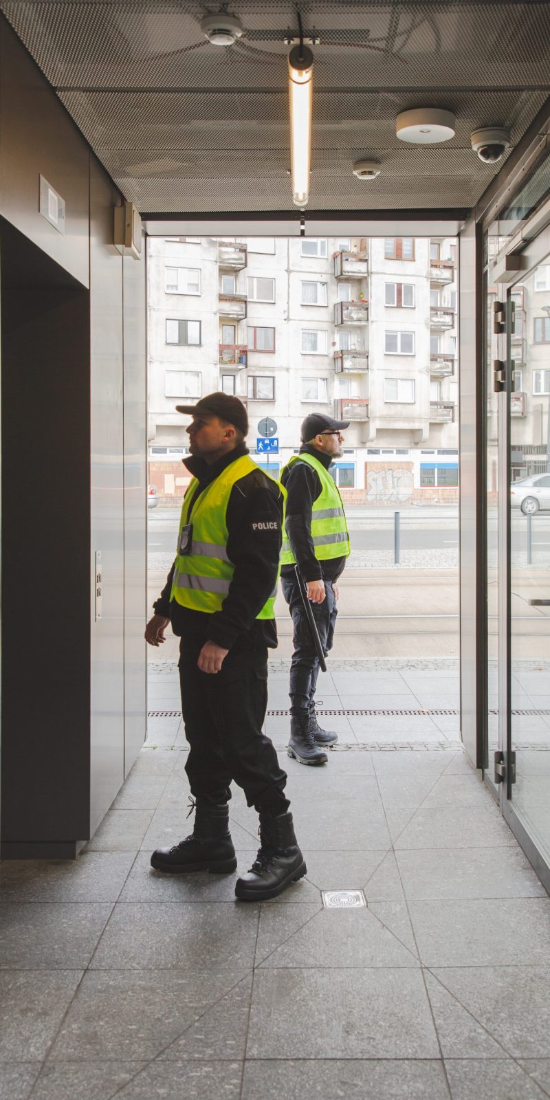 Two policemen in uniforms searching the building looking for  a suspect